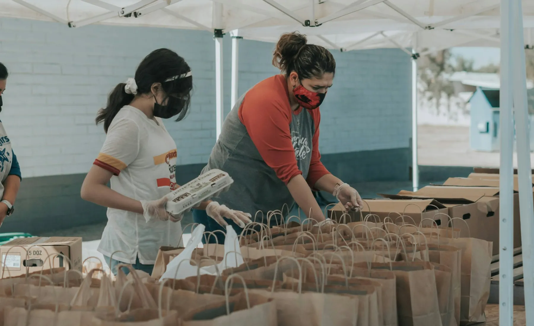Volunteers packing paper bags of food